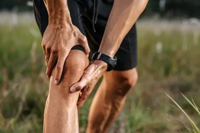 Man in sports shorts holding his knee