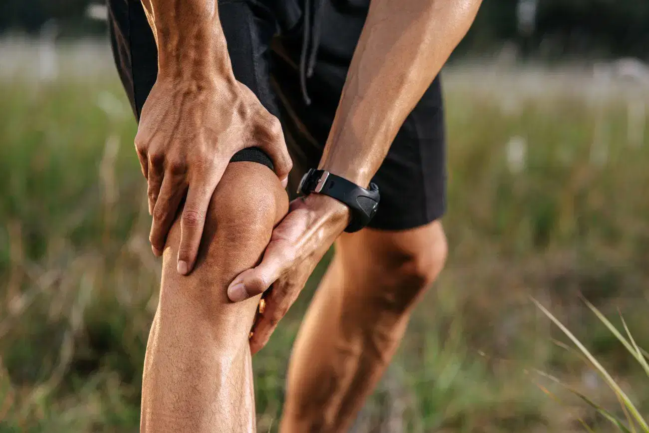 Man in sports shorts holding his knee