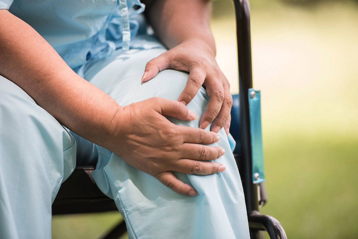 The cost of joint replacement: elderly person sitting in wheelchair with knee pain